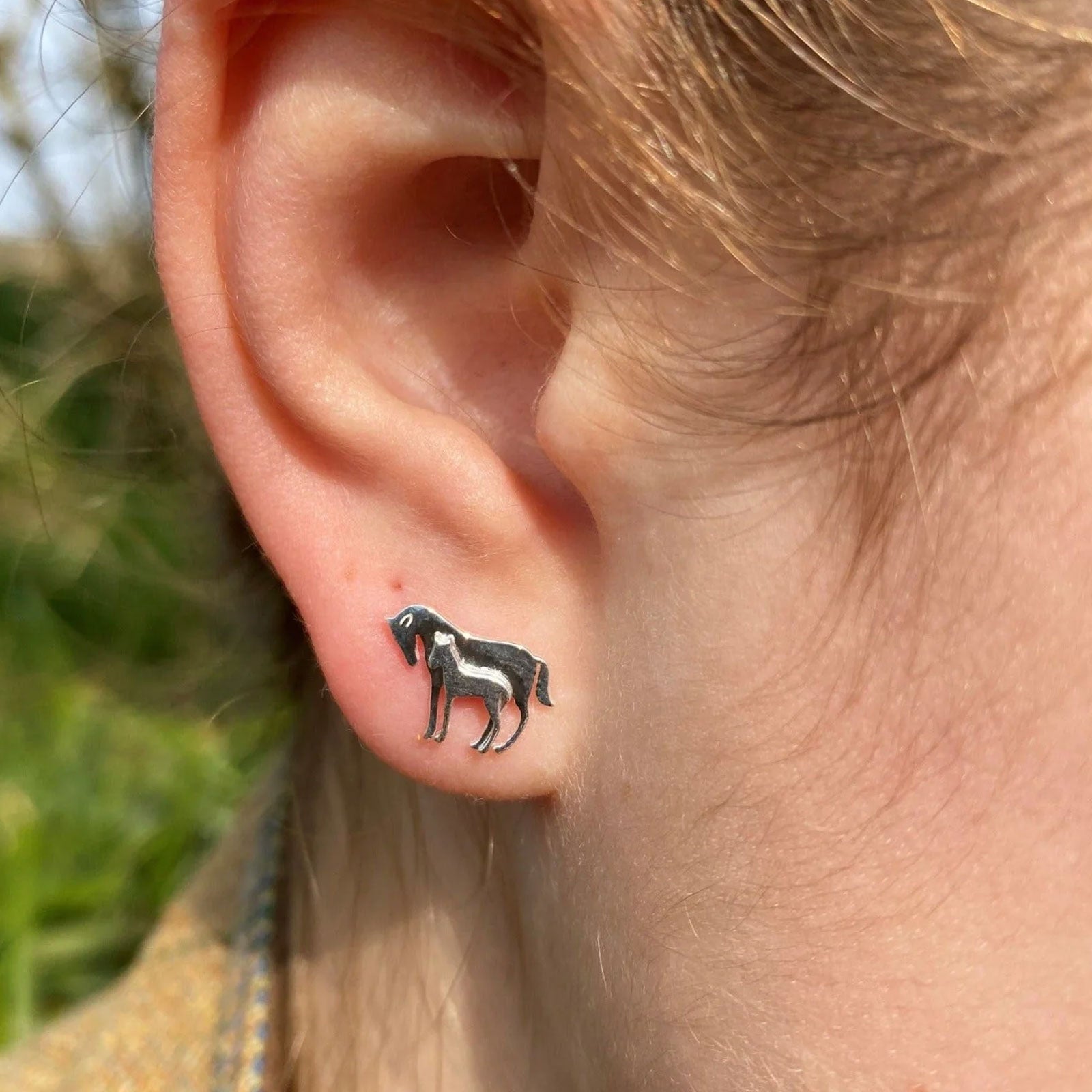 mare and foal earrings in ear of person