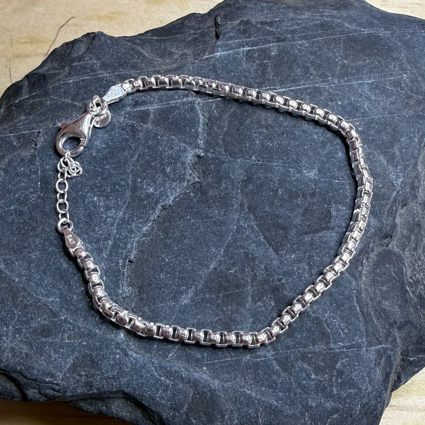 Silver bracelet on a dark stone surface
