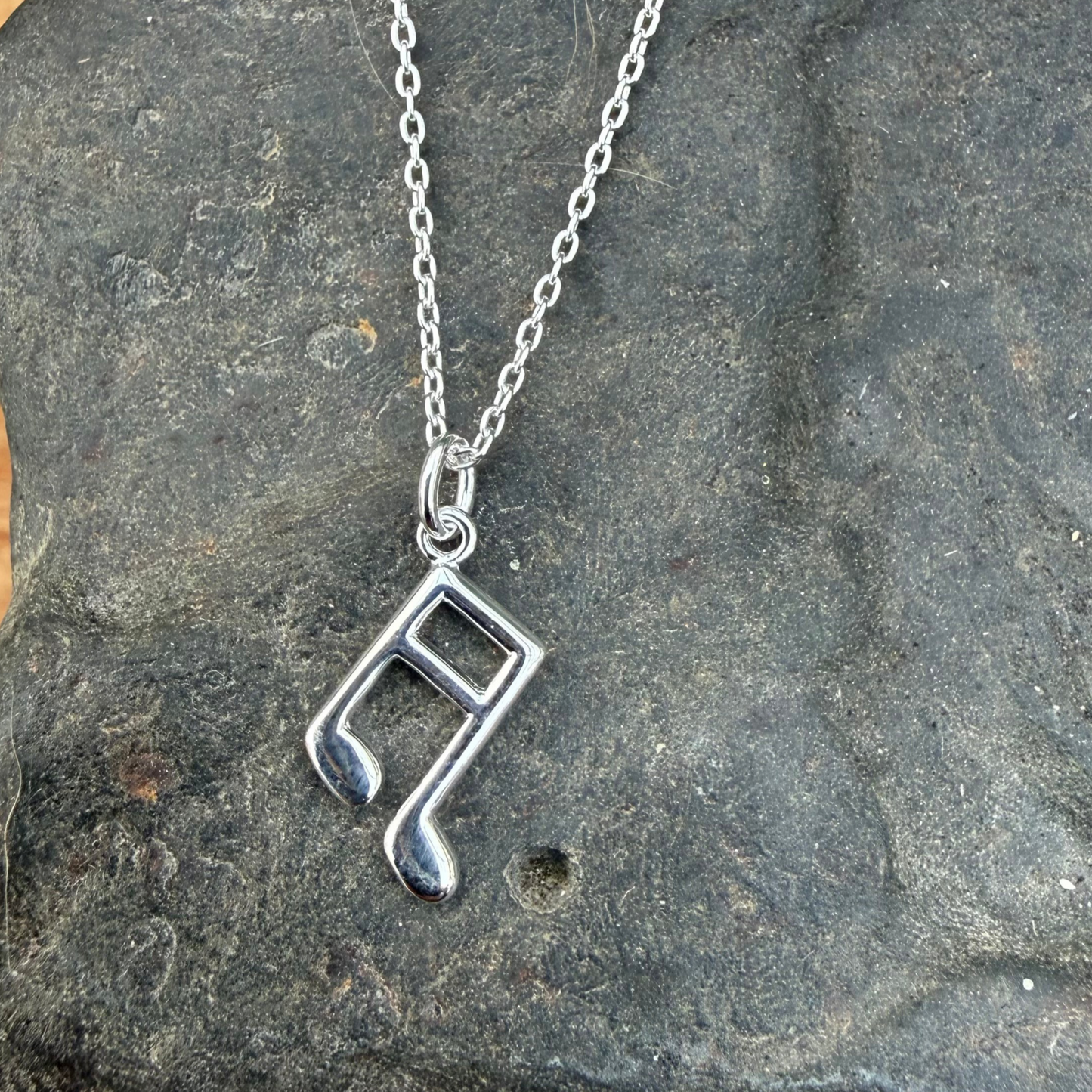 Silver necklace with a unique pendant on a stone surface