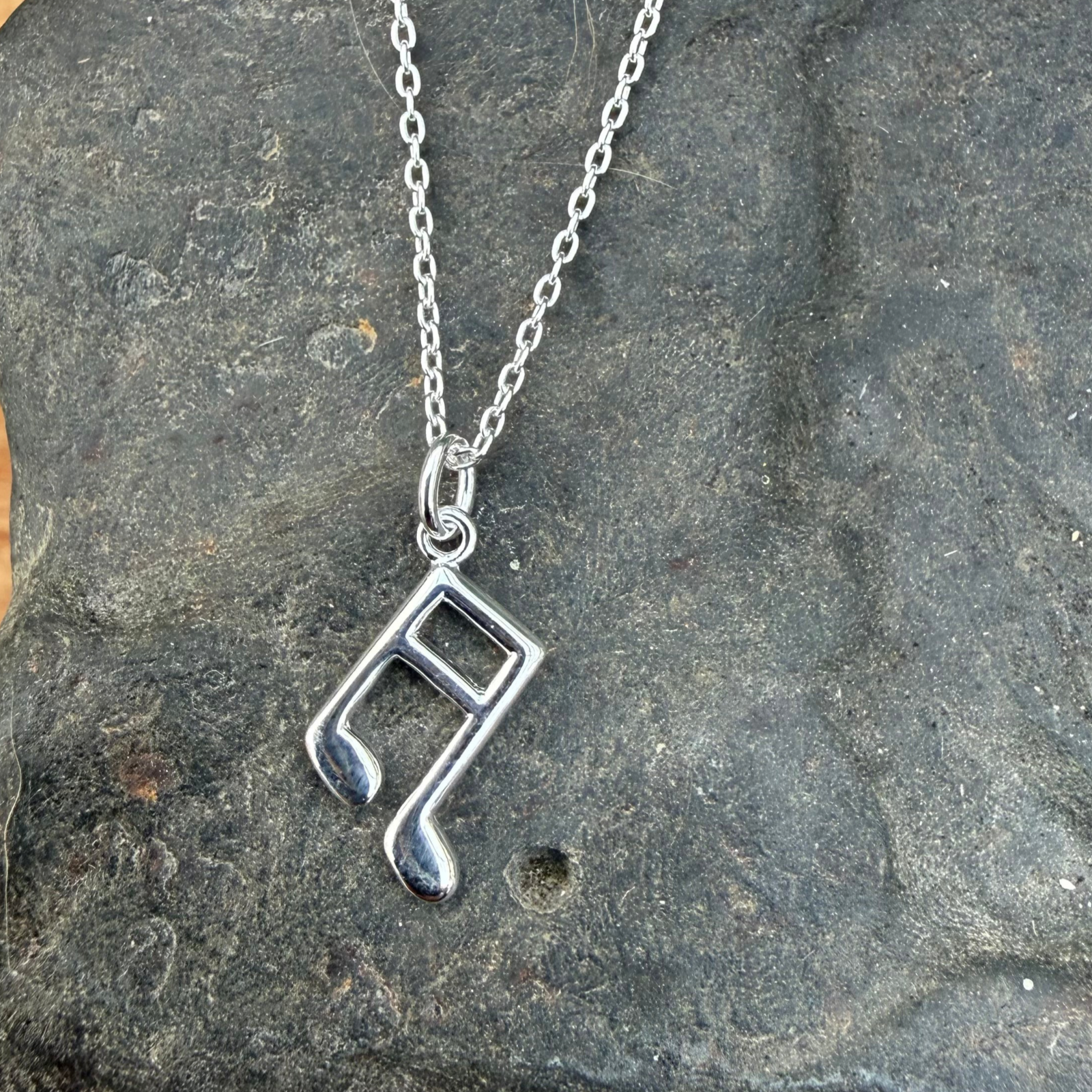 Silver necklace with a unique pendant on a stone surface