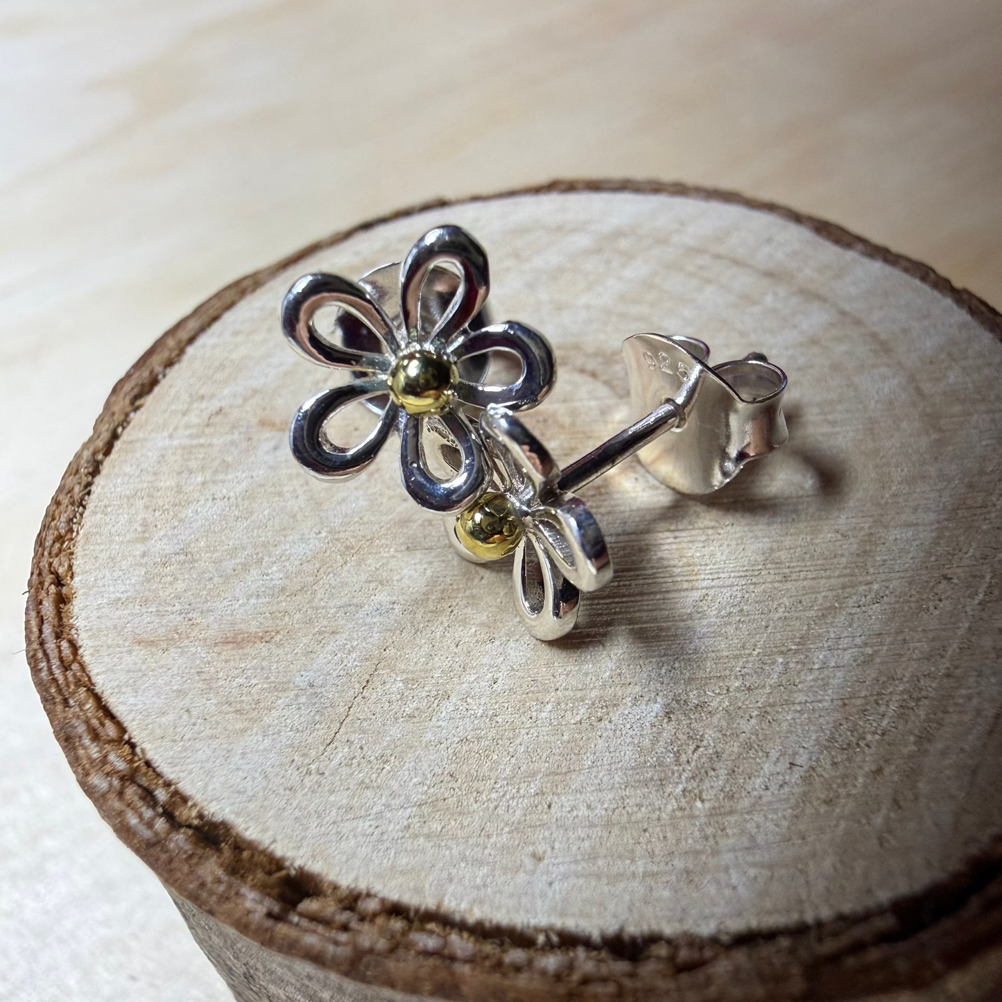 Silver flower-shaped earring on a wooden surface