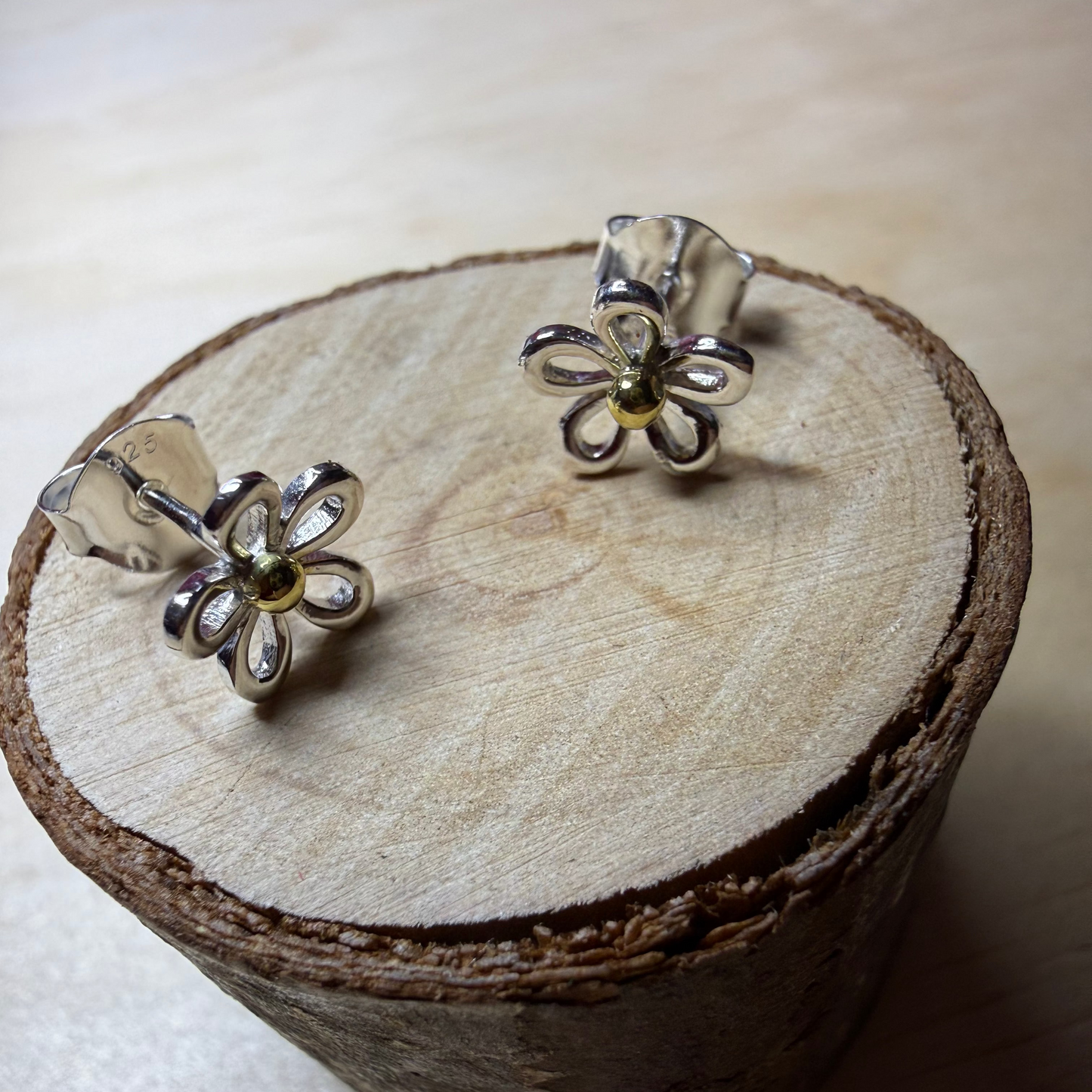 Flower-shaped silver earrings on a wooden surface