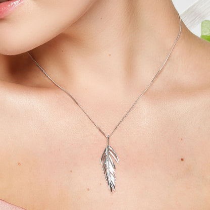Silver leaf necklace on a person's neck with a blurred background