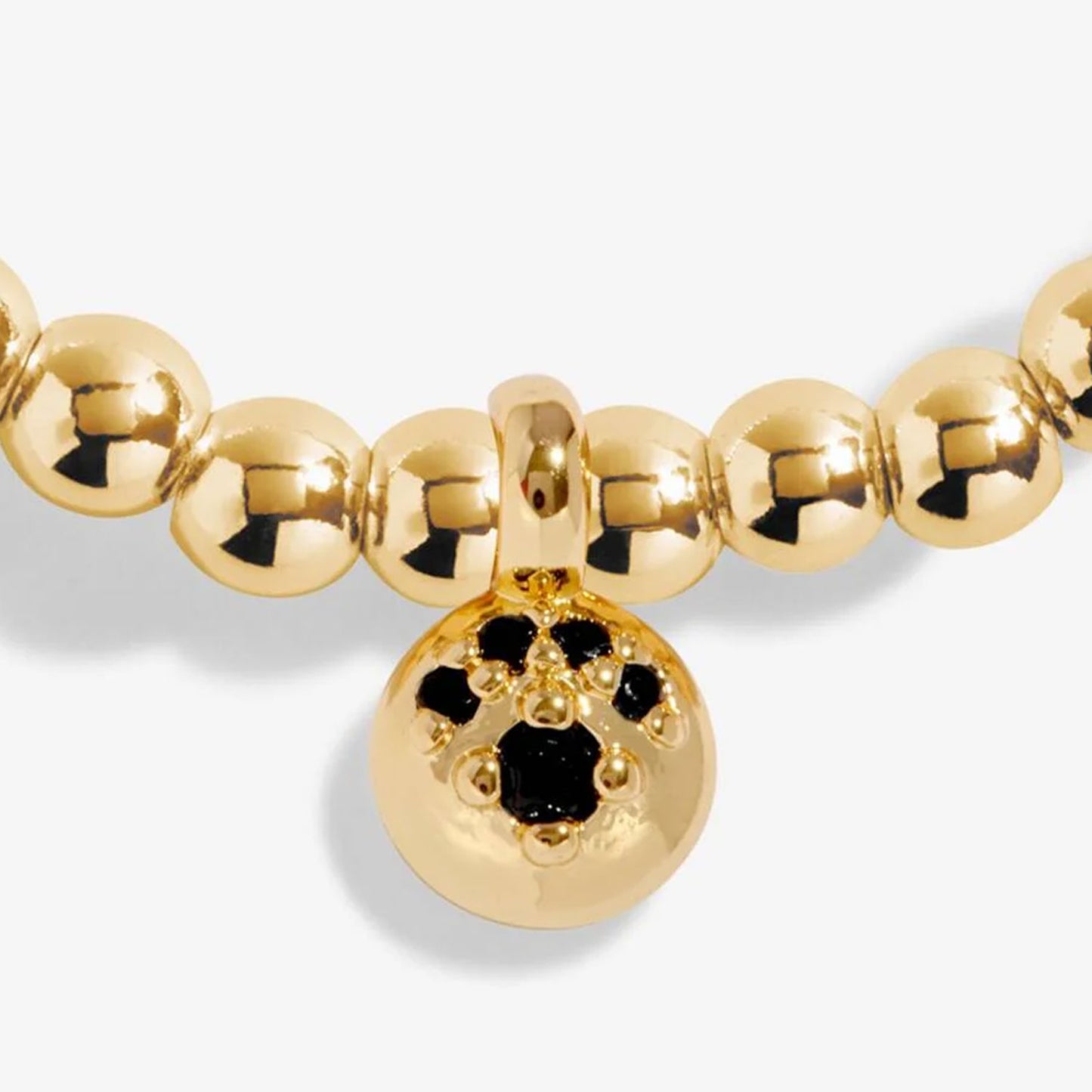 Gold beaded bracelet with a central round charm featuring black stones on a white background