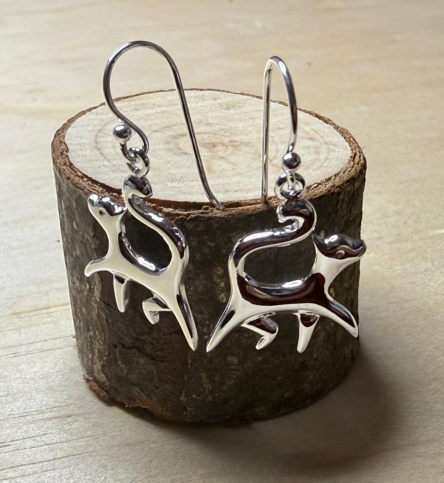 Silver cat earrings on a wooden block