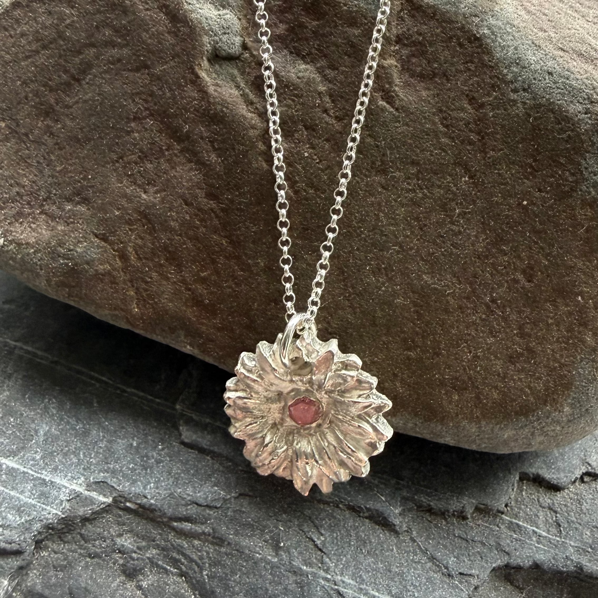 Silver necklace with a pendant on a stack of rocks