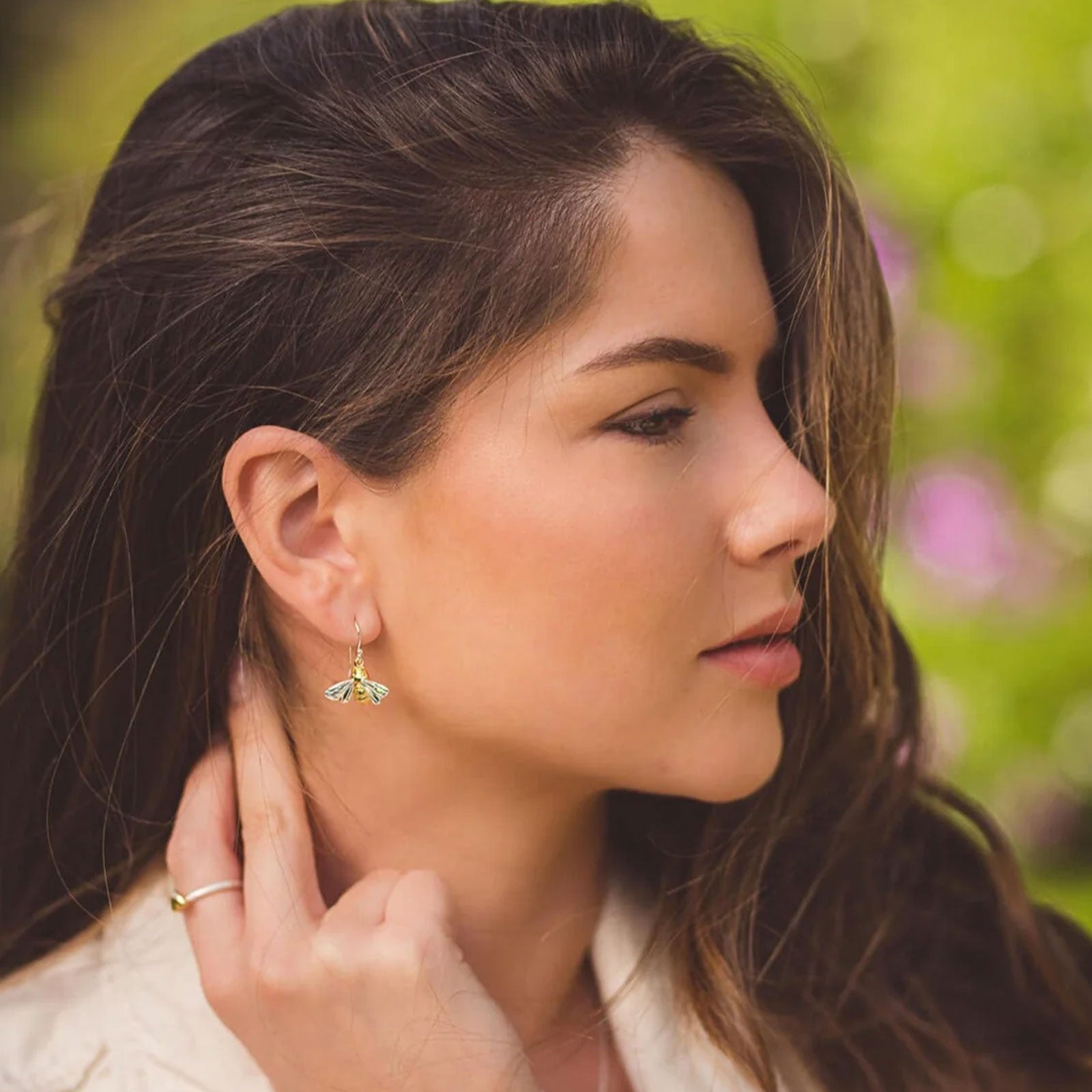 Woman wearing bee earrings with a blurred natural background