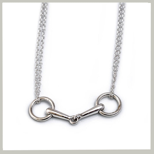 A silver horsebit necklace with a polished metal bit and chain, displayed against a clean white background.