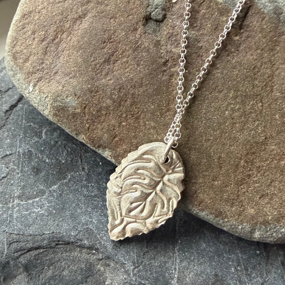 Reverse of Silver leaf necklace on a rock