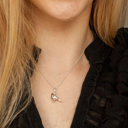 Necklace with a bird pendant worn by a person with blonde hair.
