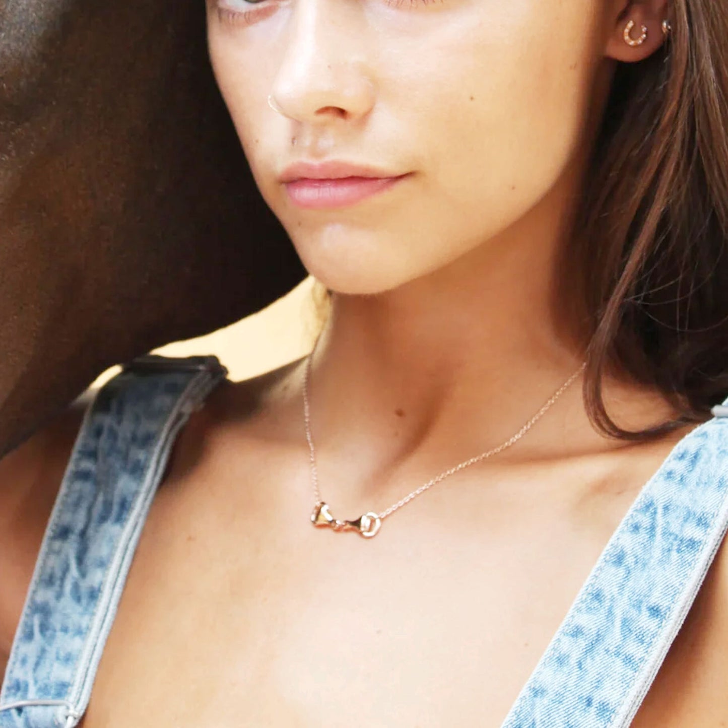 Close-up of a person wearing a gold snaffle necklace