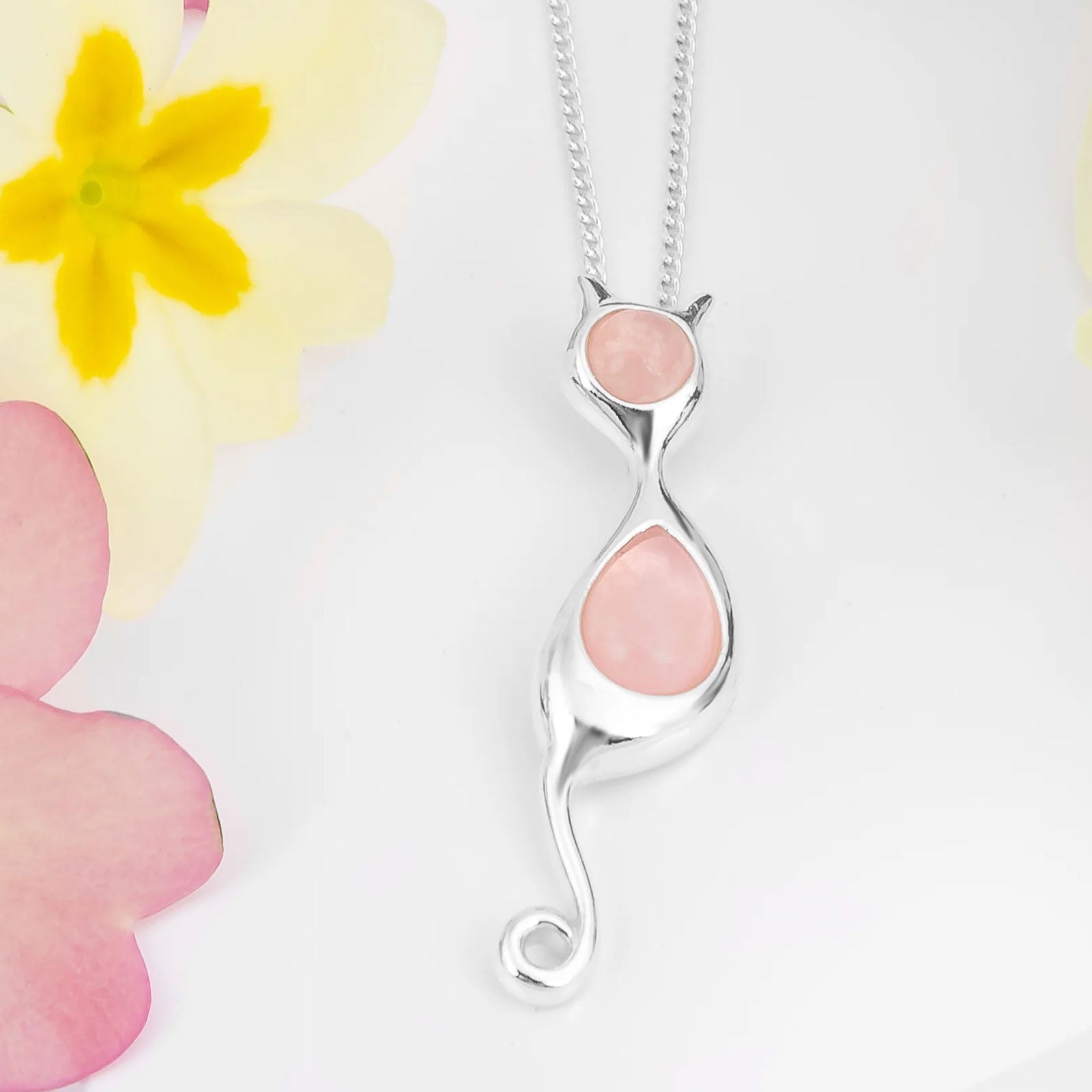Silver necklace with pink pendant against a floral background