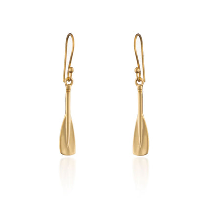 A pair of gold drop earrings shaped like stylized oar blades, suspended from matching gold fishhook wires, shown on a clean white background with a soft reflection below.