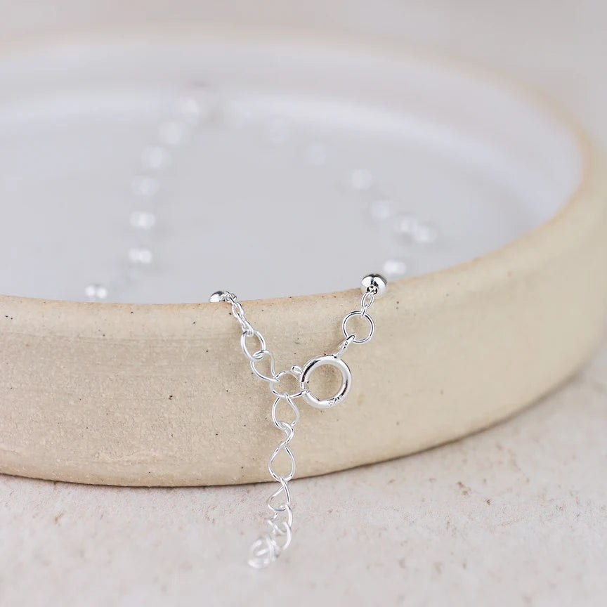 Silver bracelet on a white dish with a light background