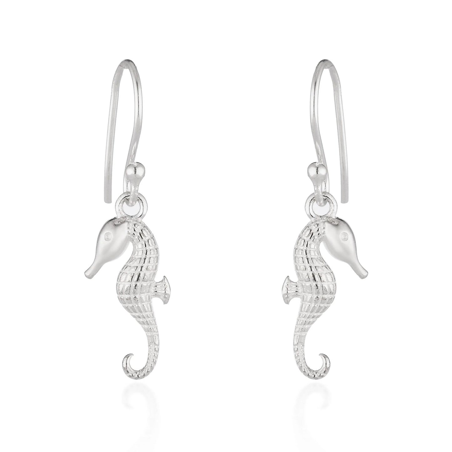 A pair of silver seahorse drop earrings with textured bodies and curved hook backs, shown on a clean white background with a soft reflection below.