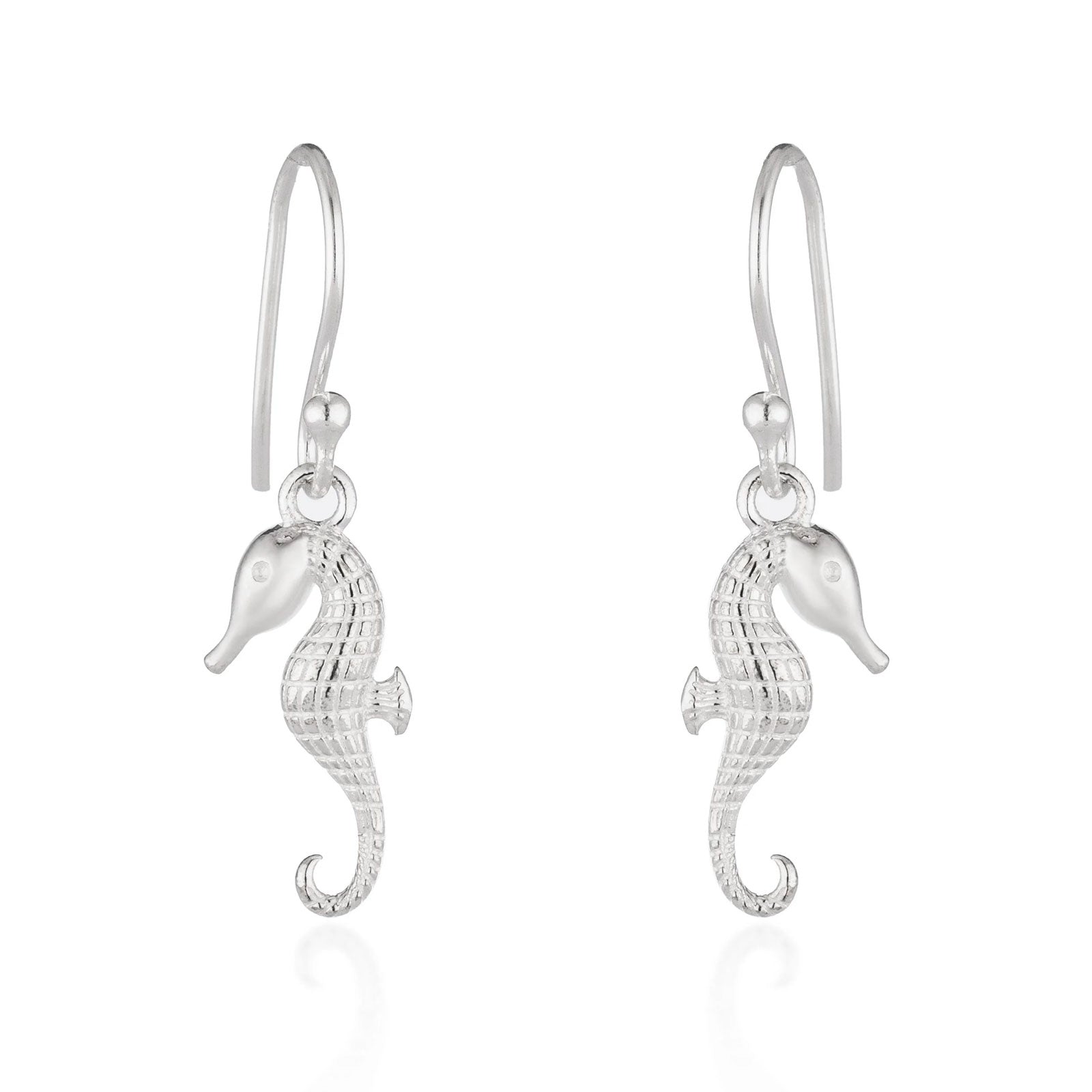 A pair of silver seahorse drop earrings with textured bodies and curved hook backs, shown on a clean white background with a soft reflection below.