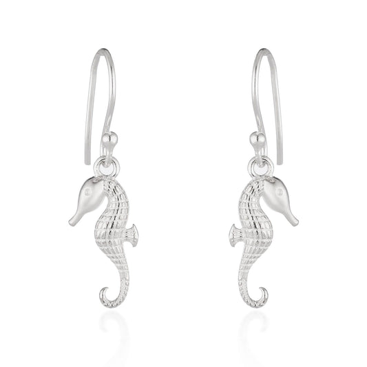 A pair of silver seahorse drop earrings with textured bodies and curved hook backs, shown on a clean white background with a soft reflection below.