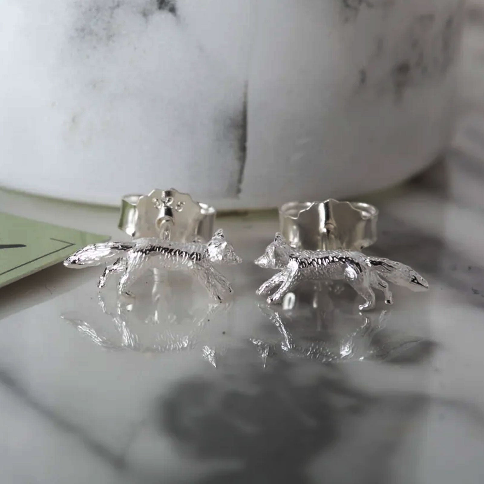 Silver fox earrings on a marble surface