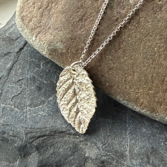 Silver leaf necklace on a stone surface