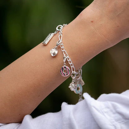 Silver bracelet with charms on a wrist against a blurred green background