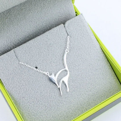 Silver bird-shaped necklace on a gray fabric surface