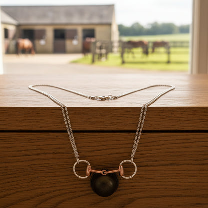 Necklace with a rose gold horse bit pendant on a white background