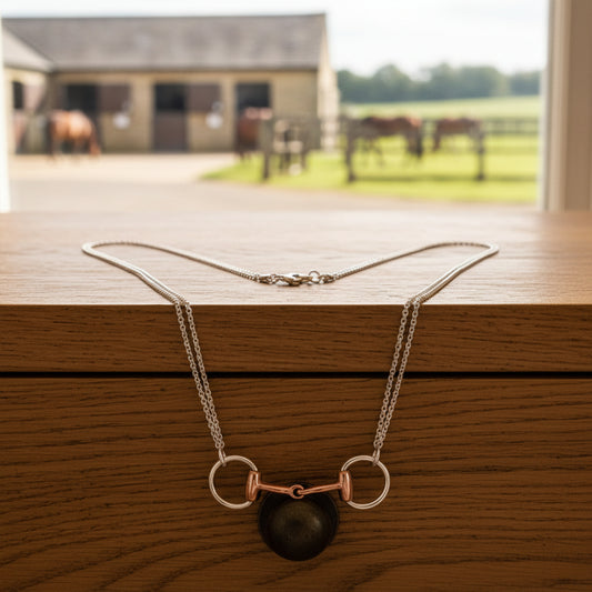 Necklace with a rose gold horse bit pendant on a white background