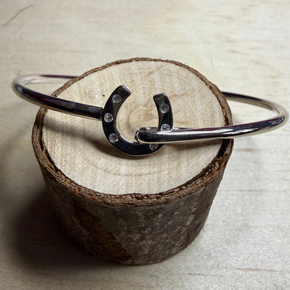Silver bracelet with a horseshoe charm on a wooden block