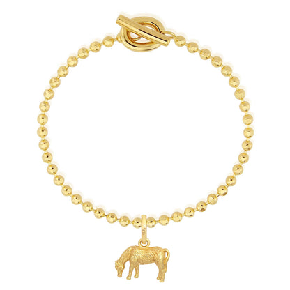 Gold bracelet with a cow charm on a white background