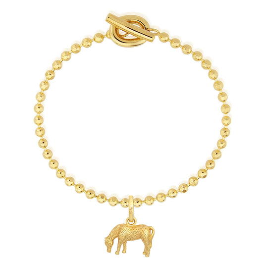 Gold bracelet with a cow charm on a white background